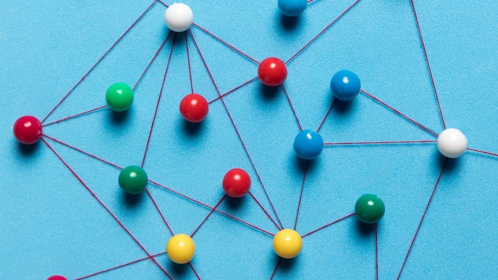 Colored pins connected by red threads forming an interconnected network on a blue background.